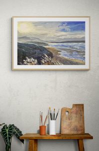sunshine and tonic framed print hanging in a wood frame on a studio wall with artist brushes and a palette on a bench