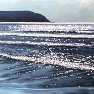 sparkling sunshine plays on the sea at Woolacombe, North Devon with Baggy Point in the distance