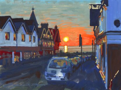 sunset over the sea viewed down a street with cars parked on the right and a hotel at the end