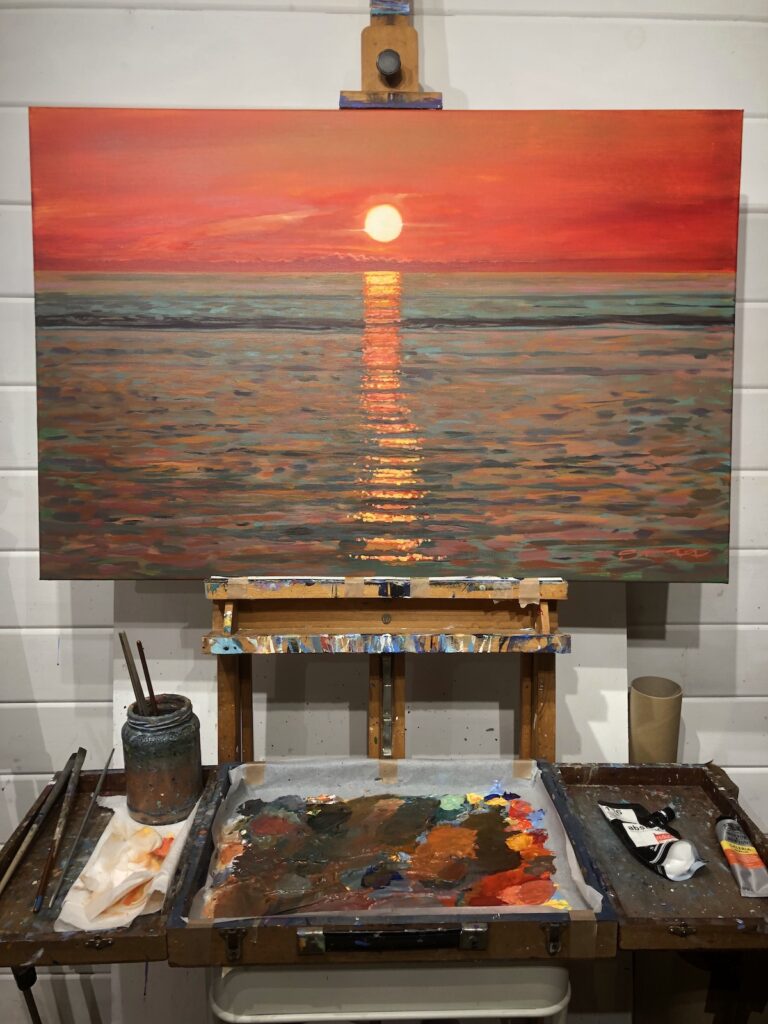 sunset painting on an easel in an artist's studio