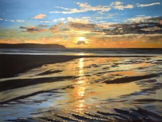 Colourful winter sunset painting reflecting in the wet sand on Woolacombe beach