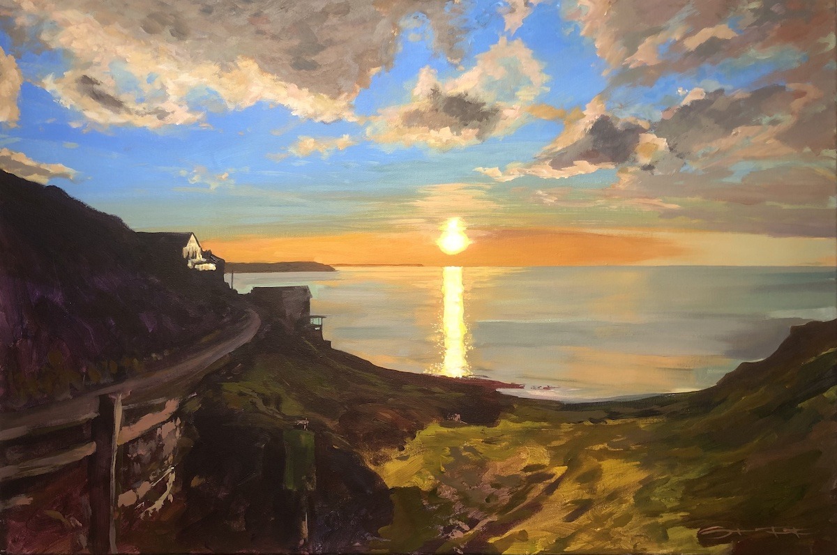 Golden sunset over the sea views from the shore with houses in silhouette on the coastal hillside