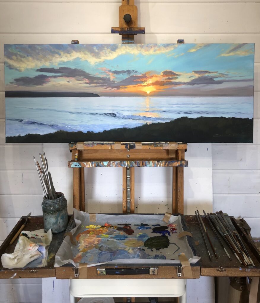 colourful painting of a sunset with waves on an artist's easel